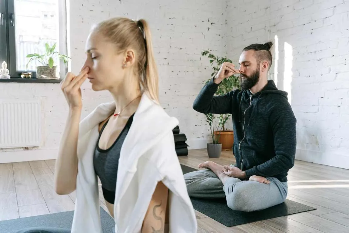 Person practising alternate nostril breathing seated with one hand raised to the nose